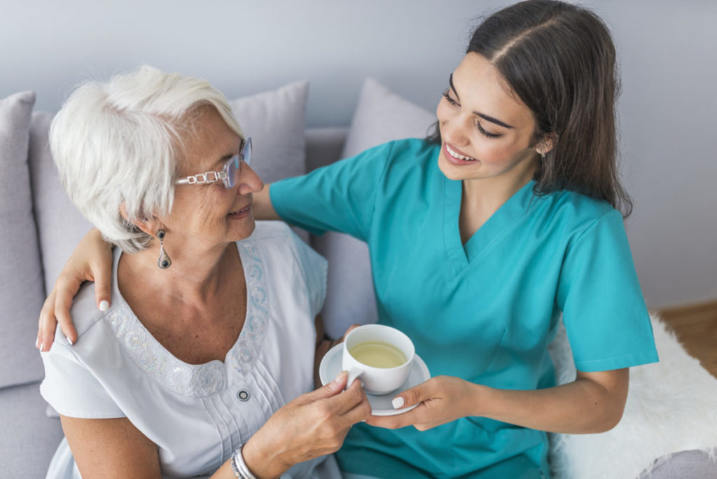 Young helpful doctor taking care of senior woman in nursing home