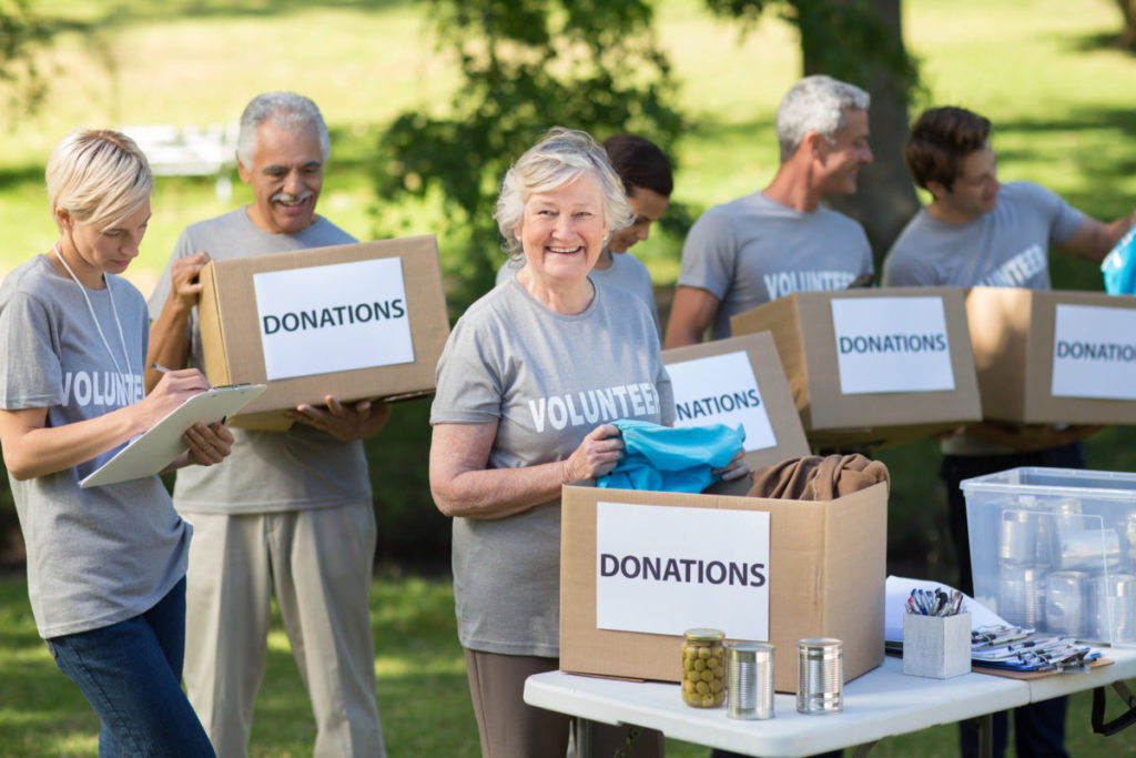 Happy family holding donations boxes on a sunny day