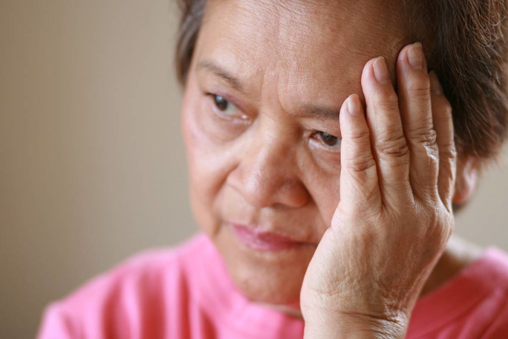 Elderly woman holding head in pain upset