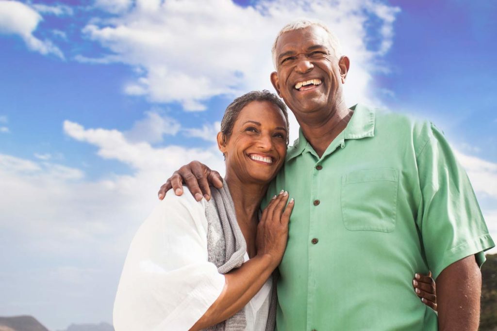 elderly couple standing together on beach