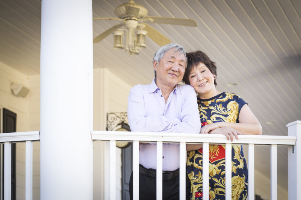 Attractive Happy Chinese Couple Enjoying Their House Outside.