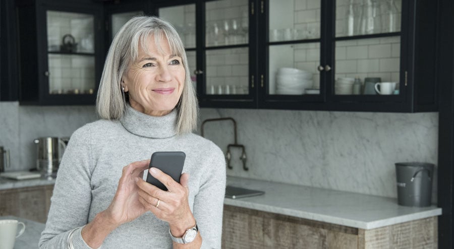 Senior holding phone in the kitchen