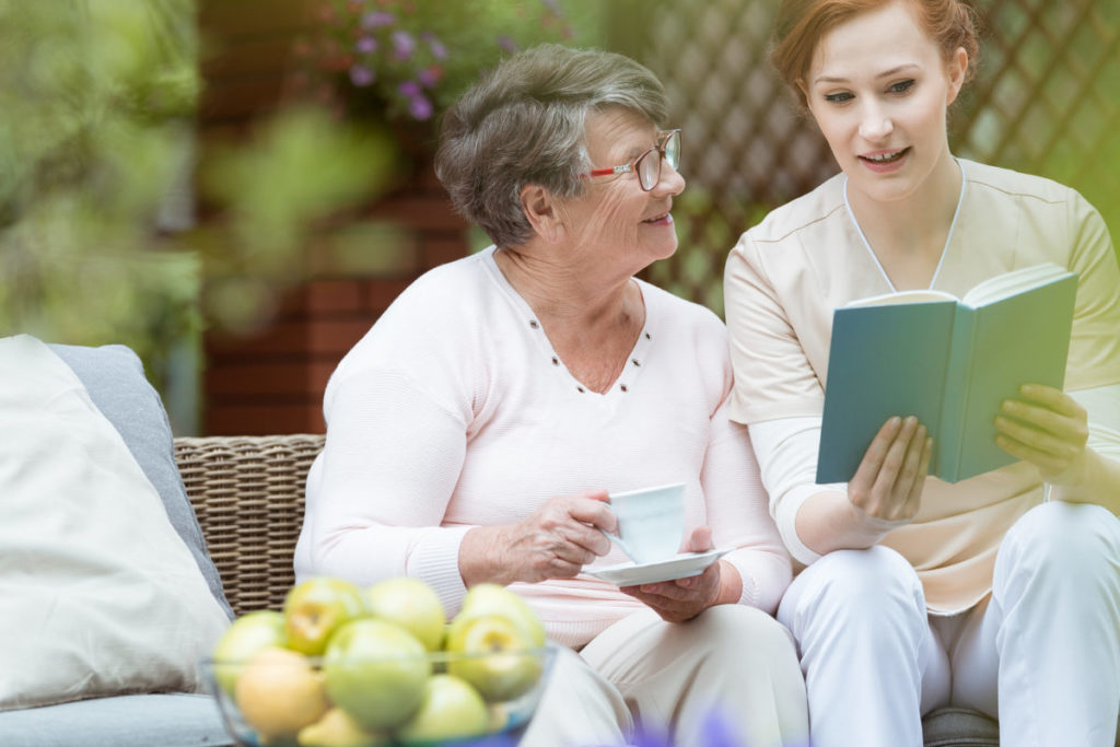 Nurse reading to pensioner