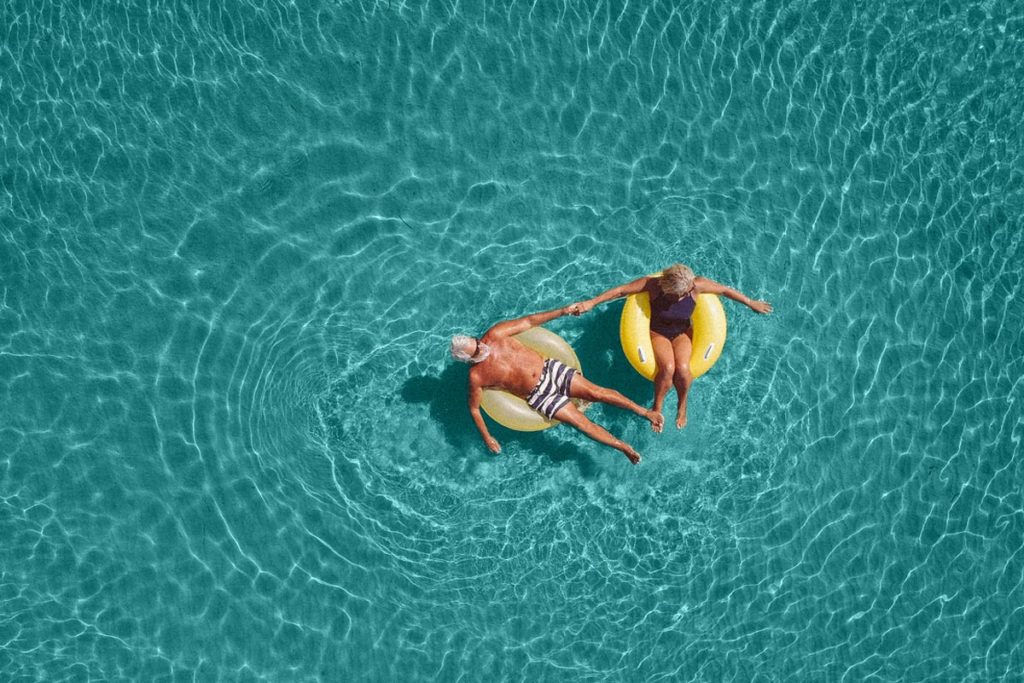 elderly couple floating in pool during retirement