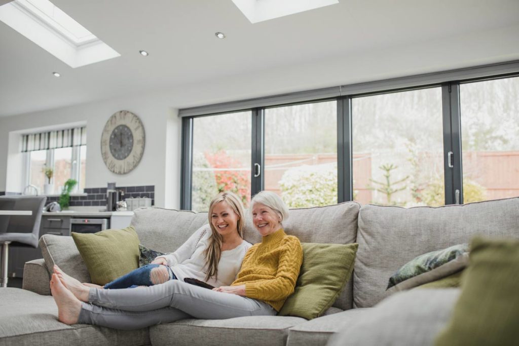 senior with daughter watching tv on couch