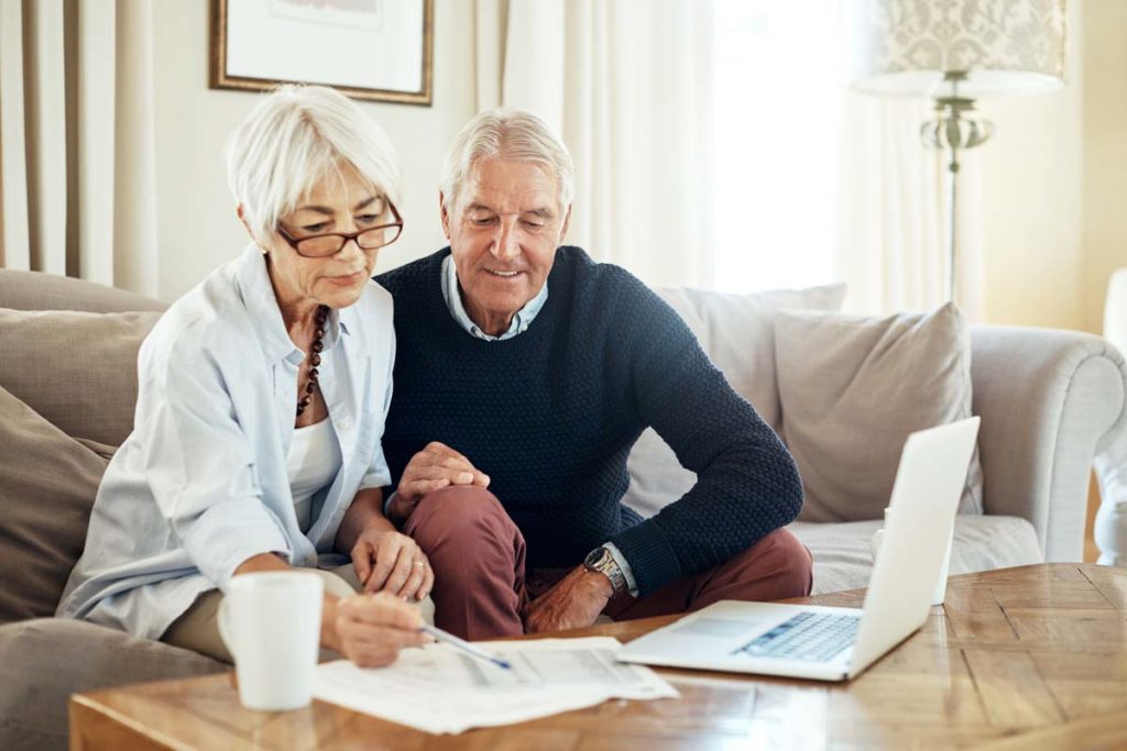 Elderly couple on computer writing notes