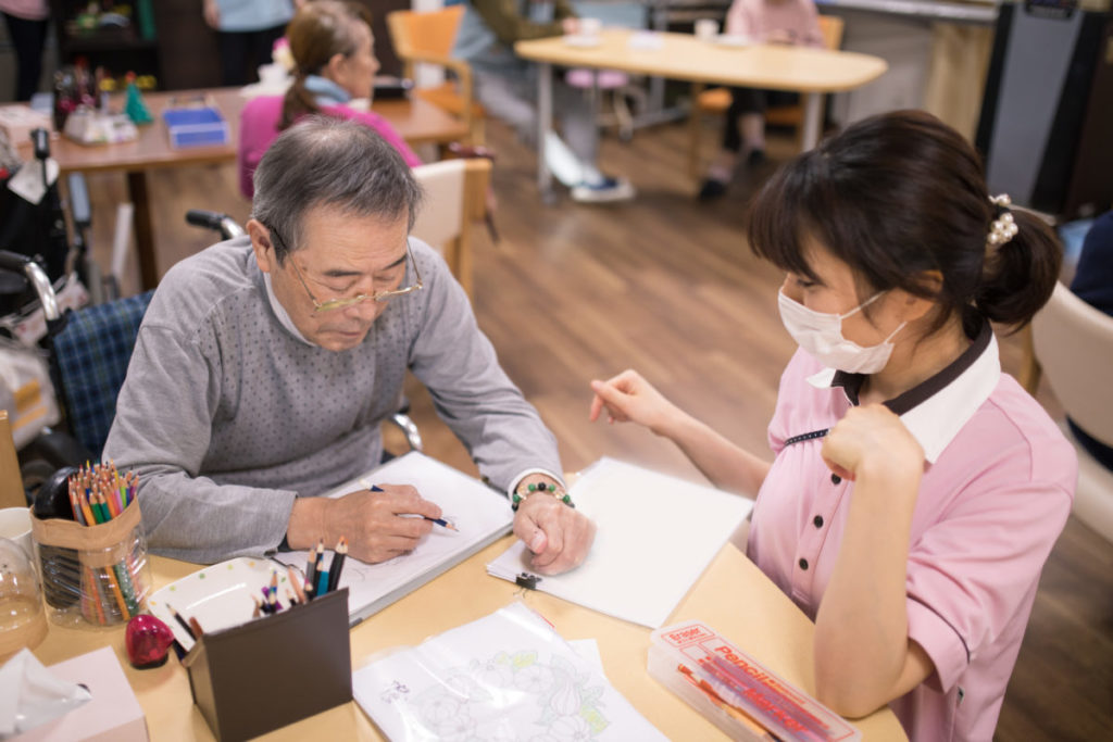 Female Asian nurse assisting East Asian male patient to draw