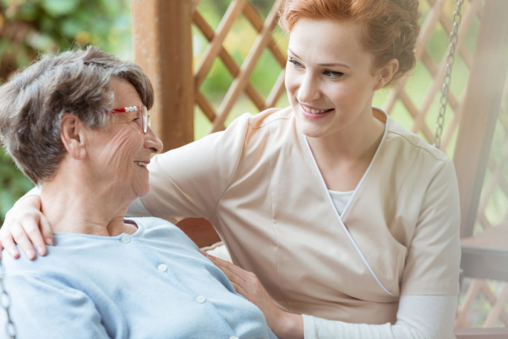 Caucasian female nurse looking at smiling Caucasian senior