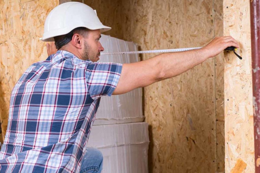 construction worker measuring width of door