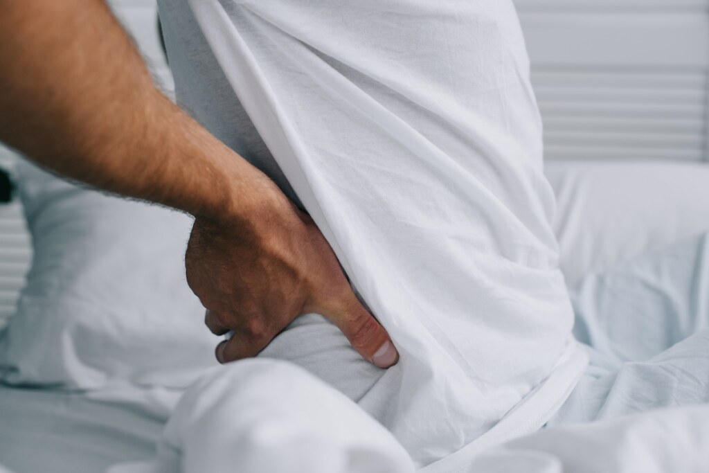 A man with osteoarthritis siting on an adjustable bed