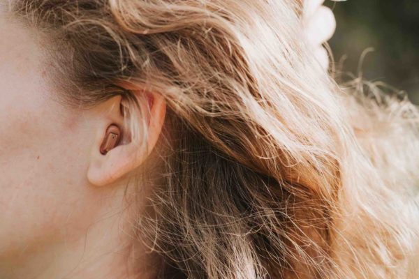 small intra channel hearing aid in the ear of a woman