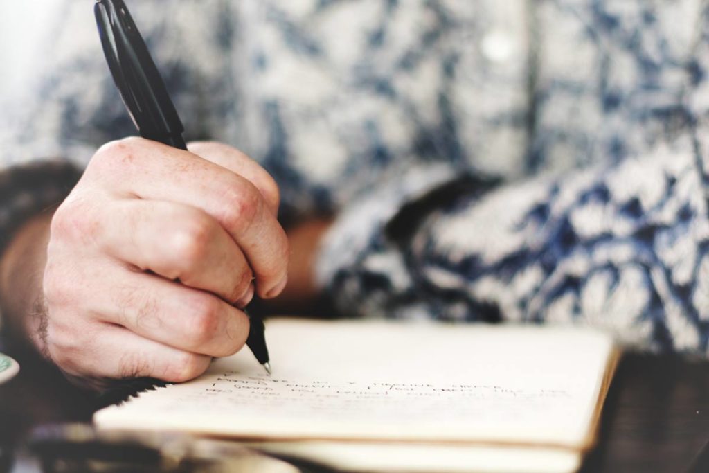 man writing in notebook