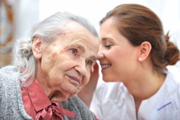 Female nurse is speaking in senior woman ear