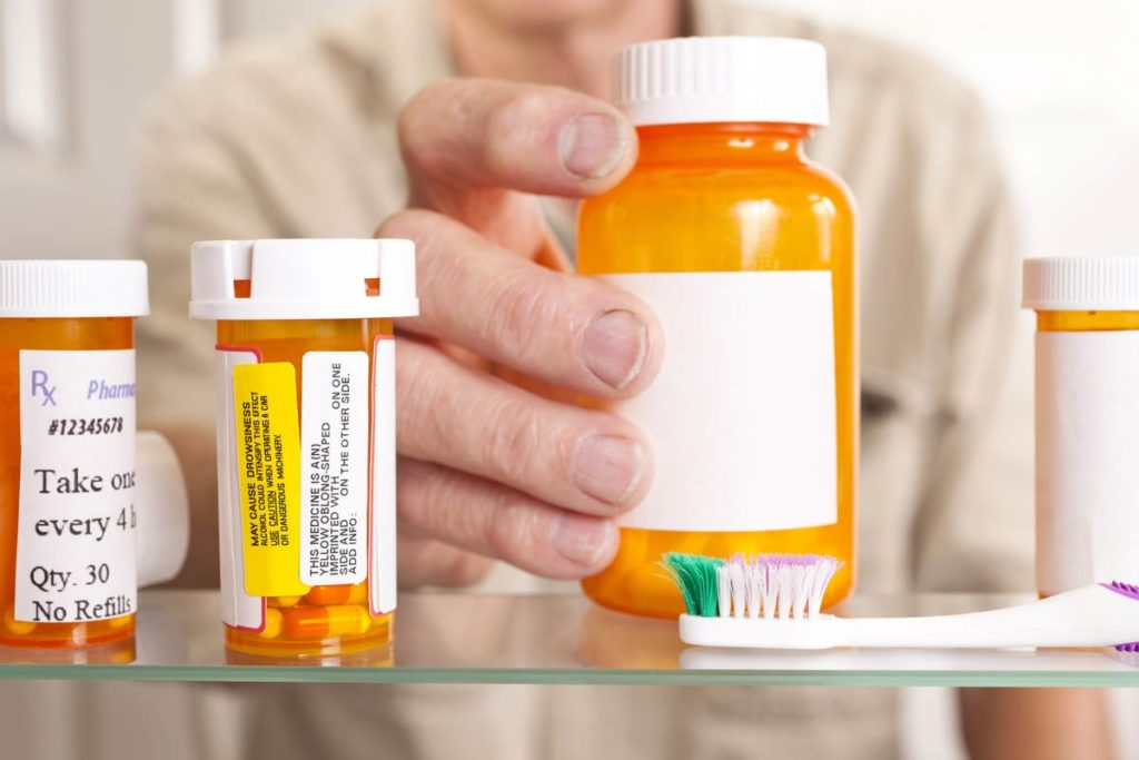 older man reaching for pill bottle