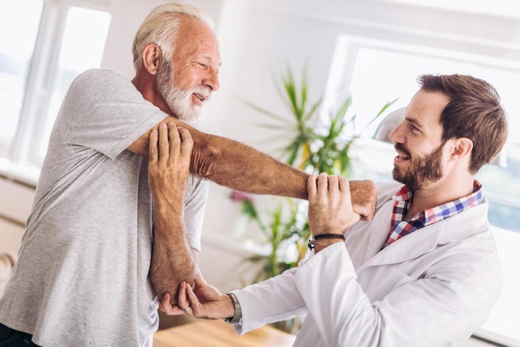 Man having chiropractic arm adjustment. Physiotherapy, sport injury rehabilitation. Senior man exercises in center for chiropractic.