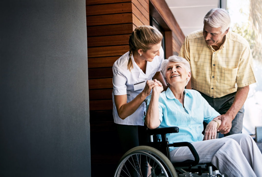 senior couple and a nurse outside a retirement home