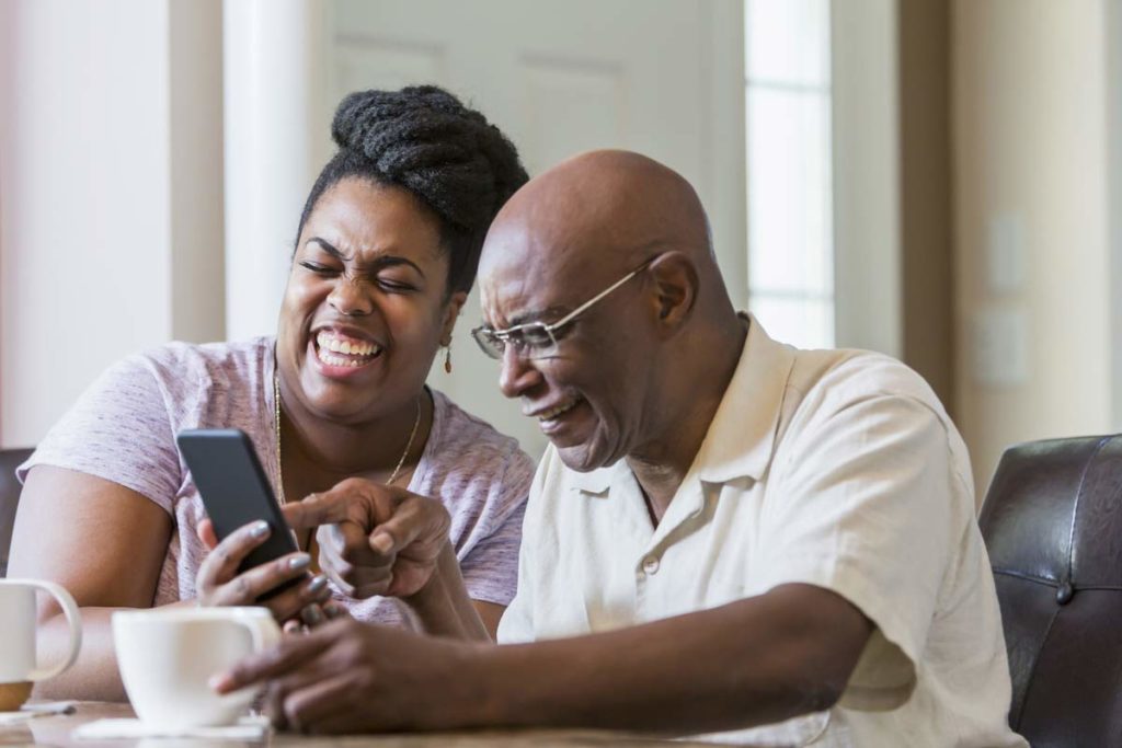 senior man and daughter laughing at smartphone