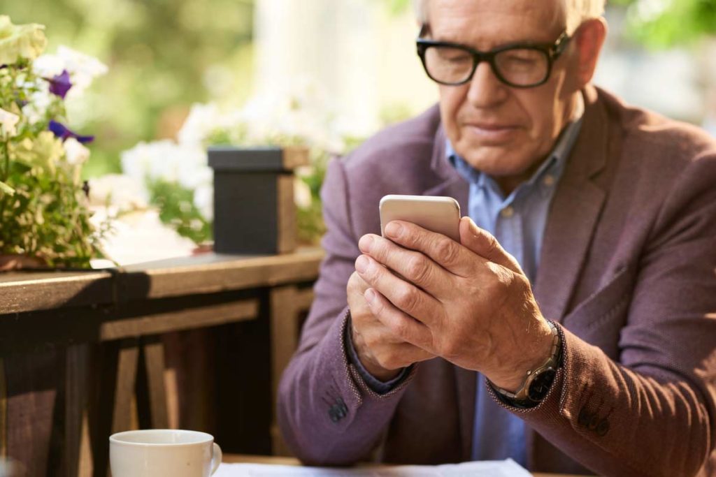 senior man on phone at cafe